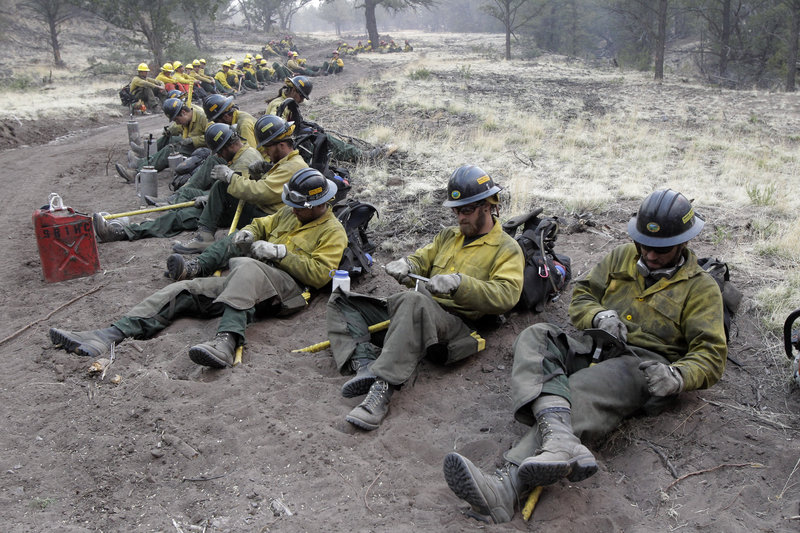 Firefighters sharpen their tools as they prepare for a back burn operation in Eagar, Ariz., on Wednesday. Winds could drive a wildfire into New Mexico, where residents of the town of Luna prepared to evacuate Thursday. Authorities said there was no containment in sight.