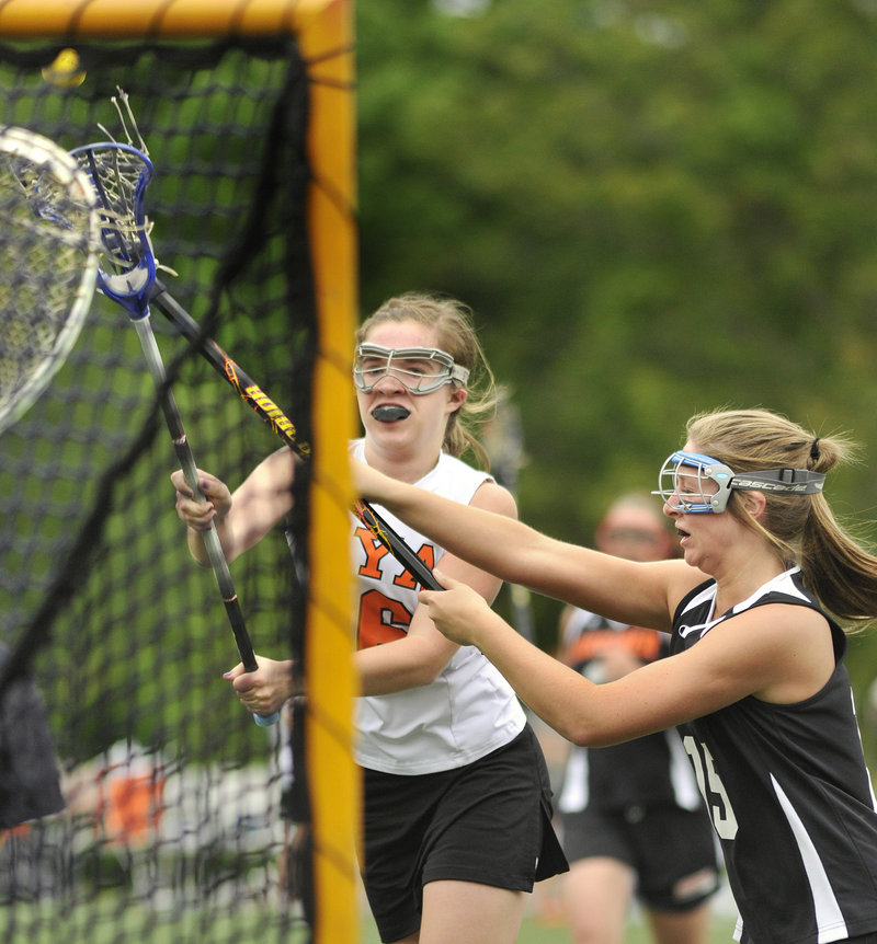 Katie Cawley of North Yarmouth Academy fires a shot on goal Saturday while defended by Paige Pillsbury of Gardiner during their Eastern Class B schoolgirl lacrosse semifinal at Yarmouth. NYA rolled to a 16-4 victory.