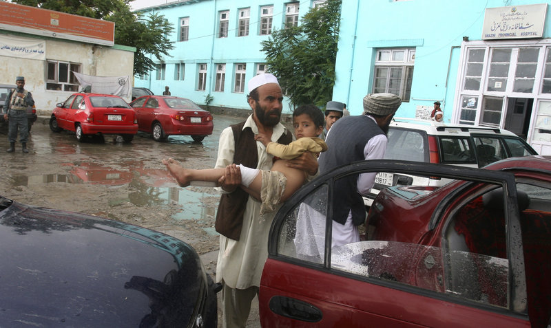 An Afghan man carries a child injured in a bombing that killed another child Saturday. The suicide blast was carried out by an attacker pushing an ice cream cart.