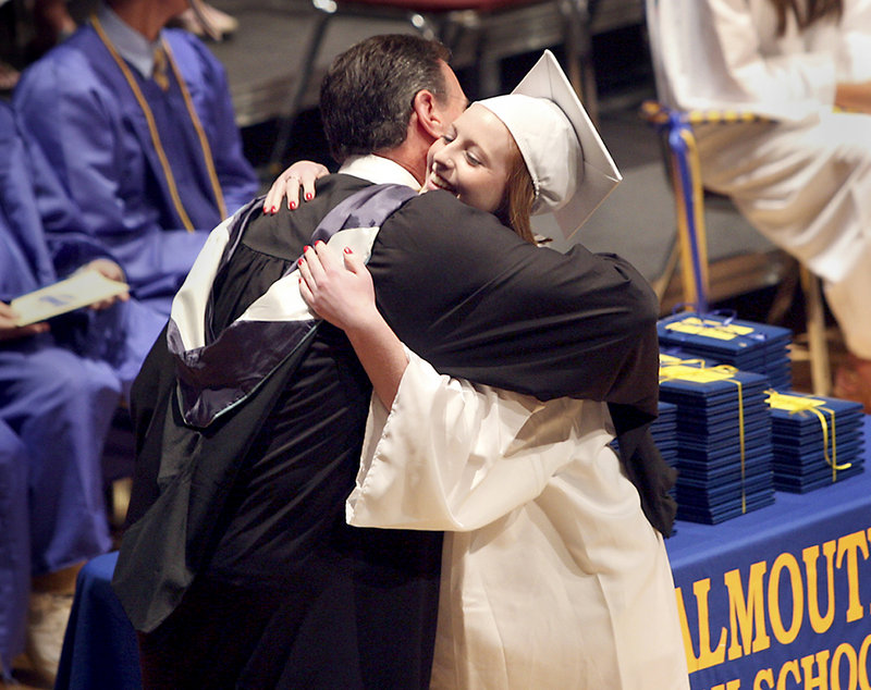 Lynzee Gillis receives a hug from Jack Hardy, Falmouth High School’s assistant principal after receiving her diploma Sunday.