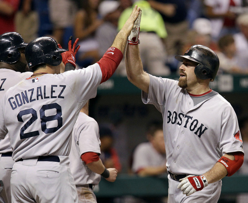 Kevin Youkilis of the Boston Red Sox, right, is welcomed by Adrian Gonzalez after hitting a three-run homer in the seventh inning of a 3-0 victory Wednesday night against Tampa Bay.