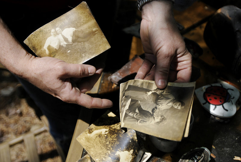 Marcia Lee flips through family photos found in the rubble where her family’s home once stood. The city has offered to dispose of the rubble but would charge the house’s owner – Doris Loomer, Lee’s mother – which would result in a lien on the property.