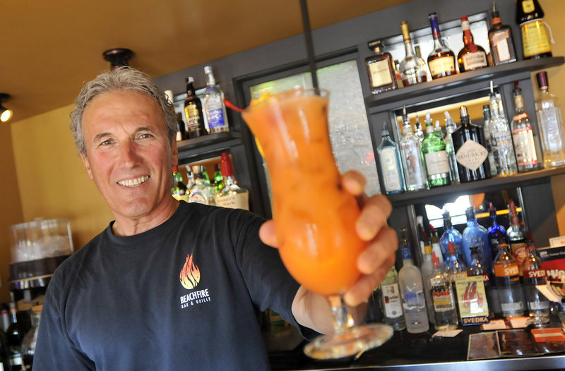 BeachFire Bar & Grille bartender Dick Dubois serves a BeachFire Rum Punch. BeachFire neatly captures the backyard/ beach/fire/BBQ feeling – only they do the work, not you.
