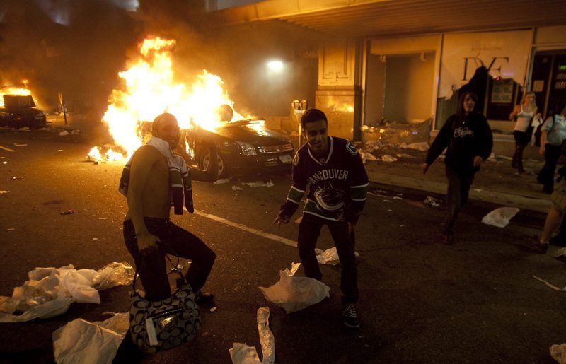 Men in Vancouver Canucks hockey jerseys are seen in downtown Vancouver, British Columbia, on Wednesday. It’s estimated more than 50 businesses were damaged and 15 cars were burned, including two police cruisers.