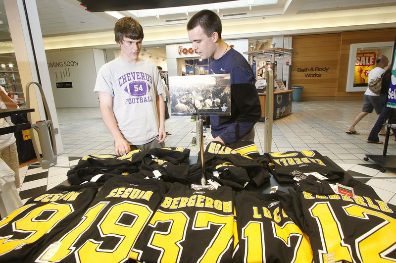 Andrew MacGillivray, left, and his brother Doug shop for Boston Bruins jerseys at Olympia Sports at the Maine Mall in South Portland on Thursday. Merchants there said “Bruins stuff has been flying out the door” as hockey fans responded to the team’s Stanley Cup victory.