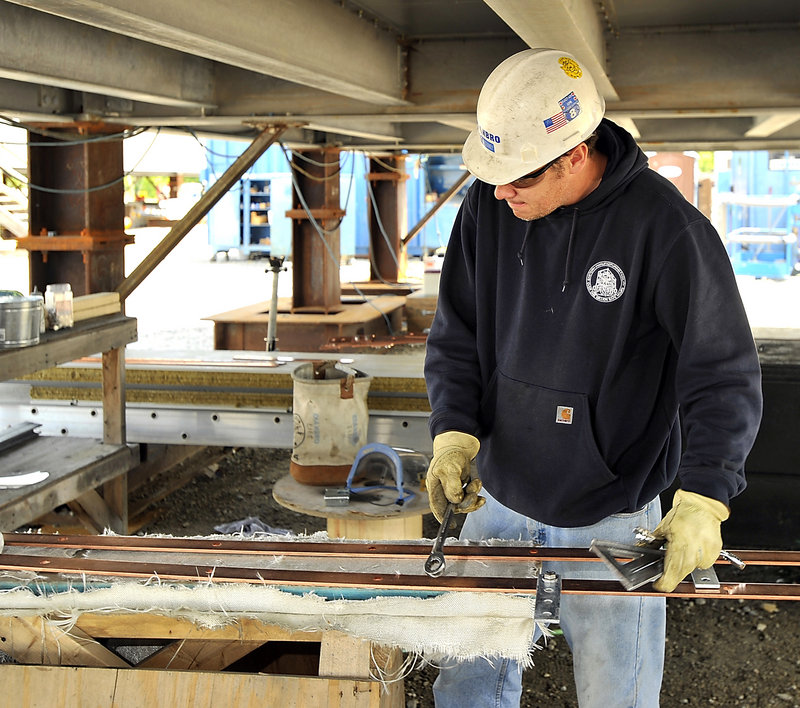 Mark Seavey, a master electrician for Cianbro, assembles a solid copper ground bar system under one of the modules.