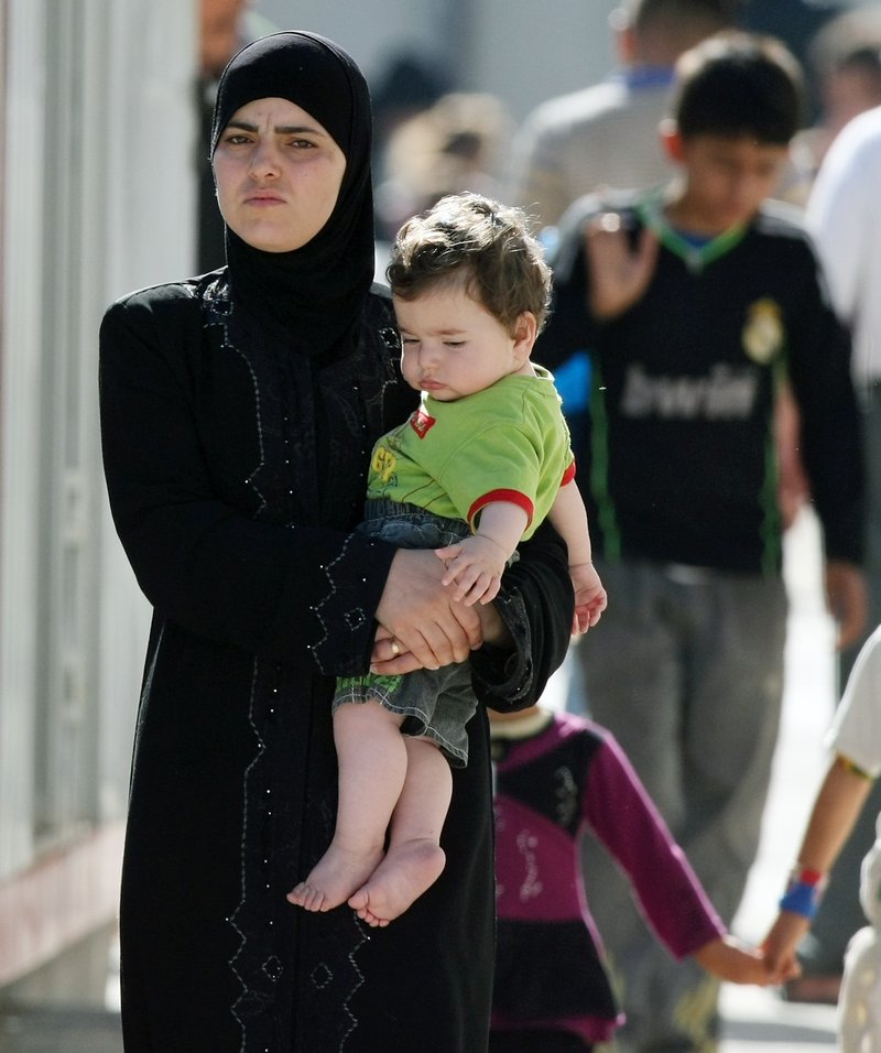 A Syrian refugee carries her child in a camp in Altinozu, Turkey, on Friday. Activists say the Syrian government has killed at least 1,400 people and detained 10,000.