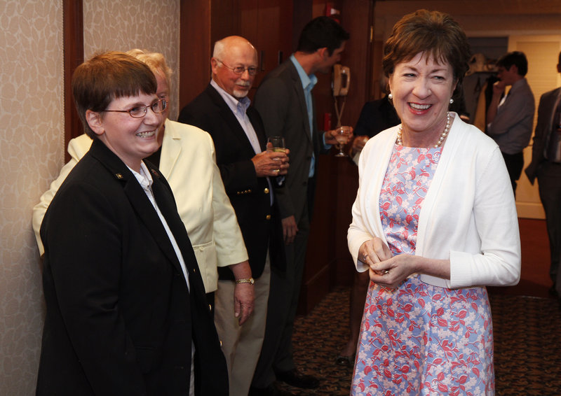 Sen. Susan Collins smiles Friday after receiving a ship's coin from Alicia Barnes at an EqualityMaine reception celebrating repeal of "don't ask, don't tell" at the Portland Regency.