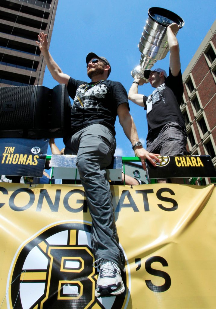 Tim Thomas, still sporting his playoff beard, waves to the crowd as Zdeno Chara holds the Stanley Cup during Saturday’s parade celebrating the Bruins’ championship.