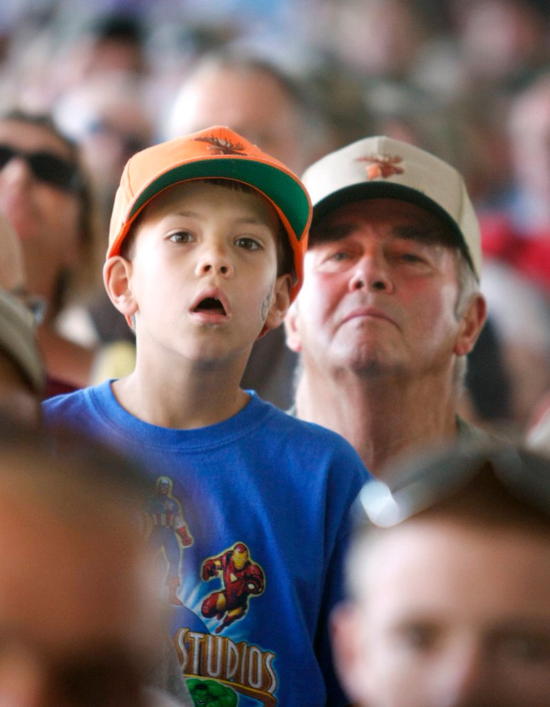 William Largey, 7, and his grandfather, Loren Largey, both of Gorham, keep a close eye on the video screen as names are called during the annual moose lottery Saturday.