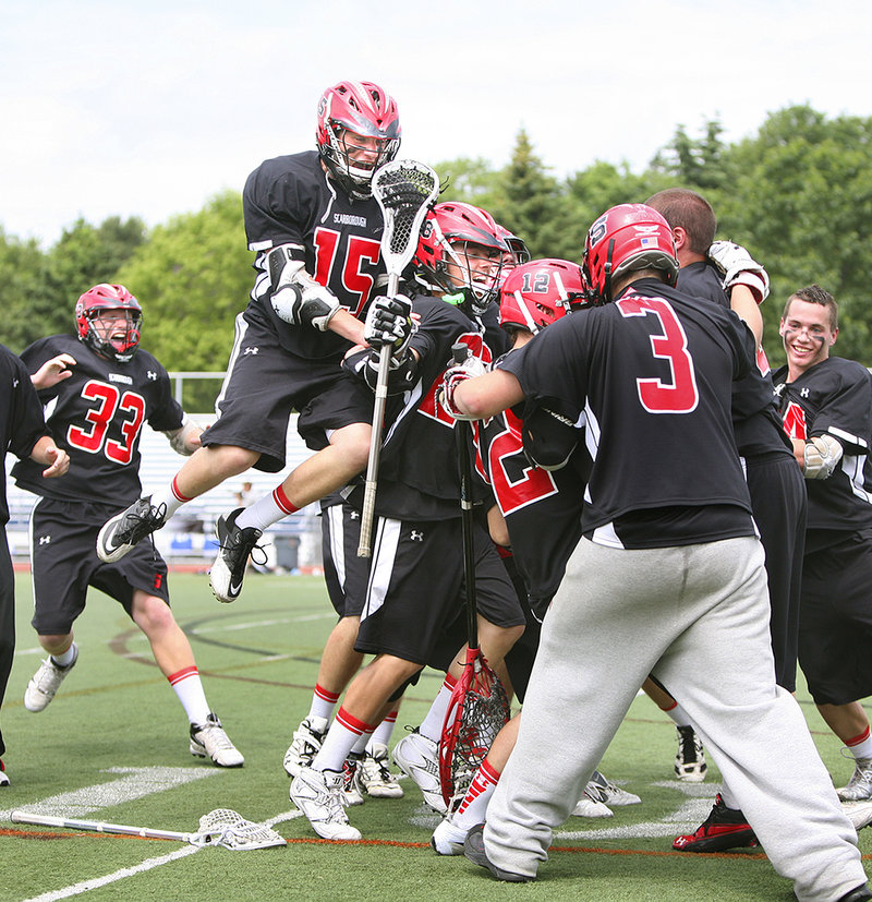 The Scarborough boys' lacrosse team prepares for Dalton Finley, left, to land on the celebratory pile after the team secured the Class A state championship Saturday with a 6-4 win over Lewiston.