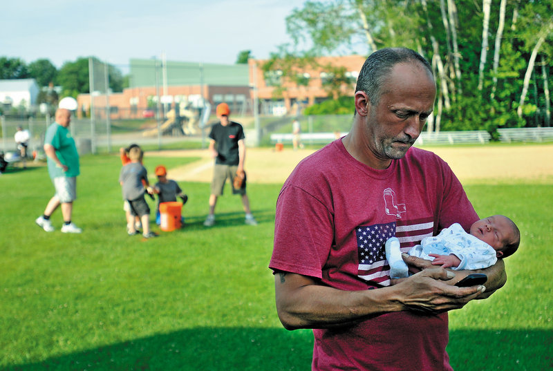 Donn Chamberlain holds his infant son, Rain, while son Bailey, 9, practices with his team in Norridgewock. "I just think it's rewarding to be home with them, be with them and not just visit them once in a while," the Skowhegan father of four said.