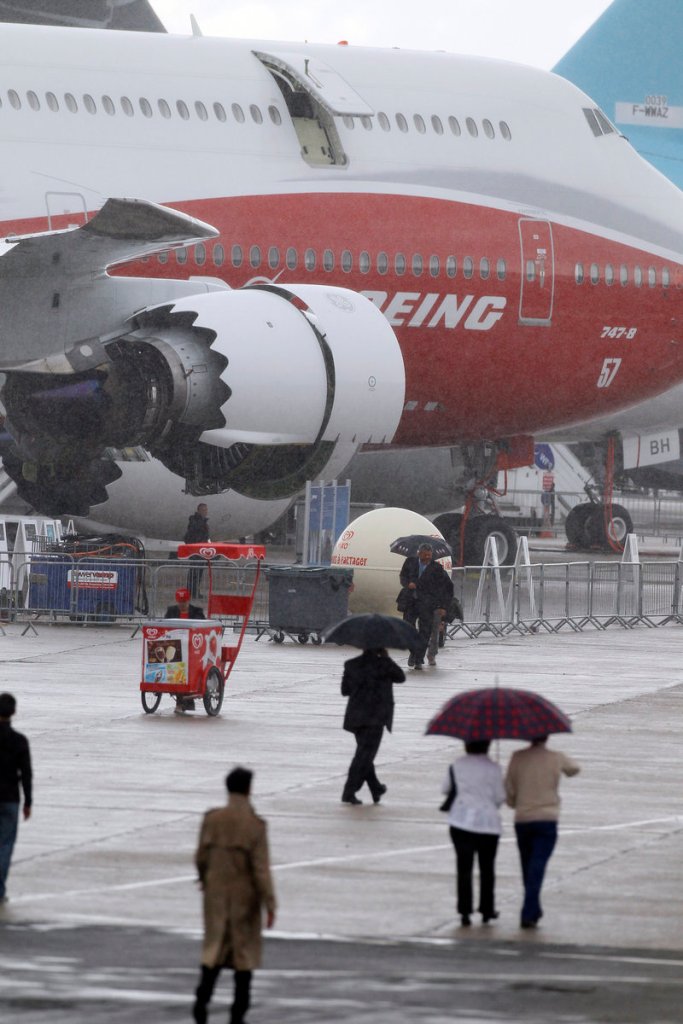 Visitors walk in the rain toward a biofuel-powered Boeing 747-8.