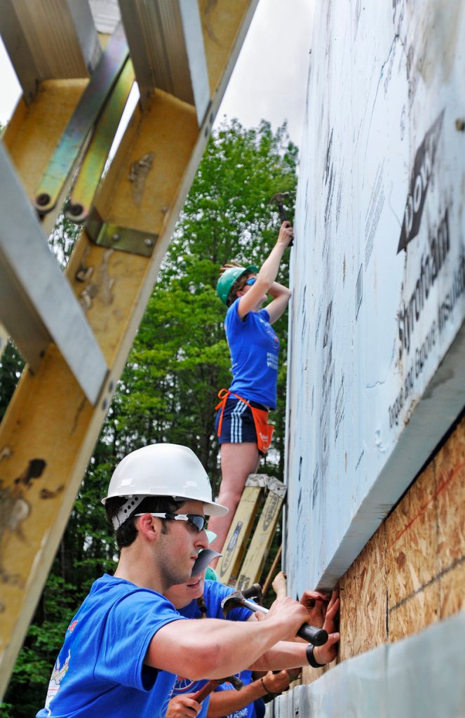 Bike & Build members Aaron Miller of Bala Cynwyd, Pa., front to back, Becky Carman of Green, Ohio, and Kate Weigel of Bangor work on a house Monday on South Street in Freeport for Habitat for Humanity.