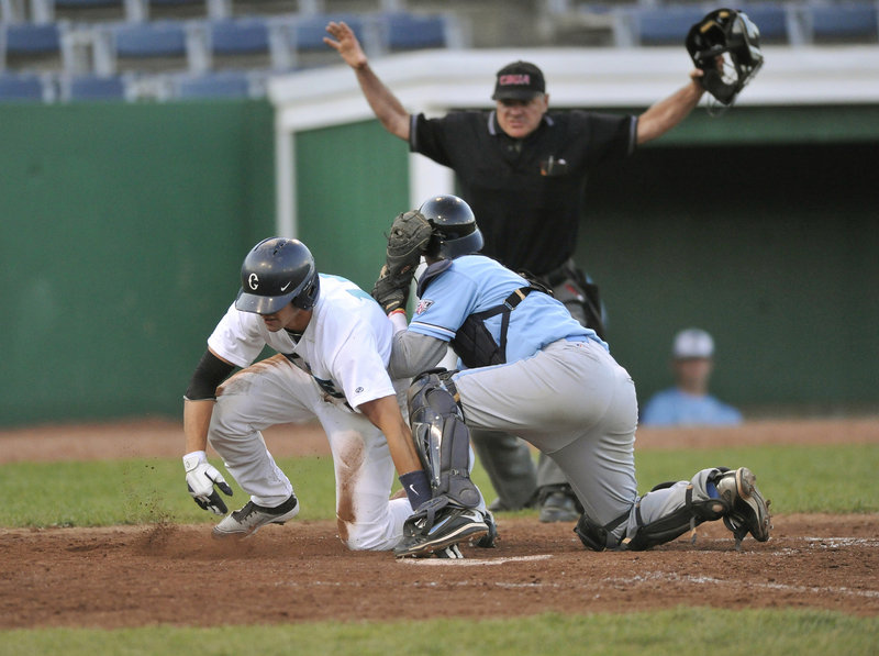 Tom Verdi of the Raging Tide gets the safe call after beating the tag by Laconia Muskrat catcher Dylan Kelly and scoring on a double by Matt Marquis in the sixth inning of a game Tuesday night at Old Orchard Beach.