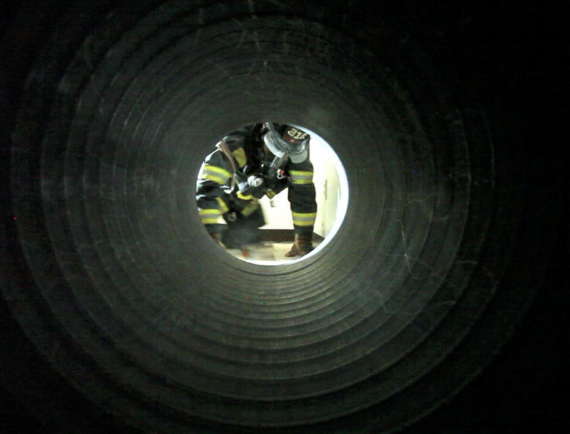 Portland firefighter Paul Decker enters a tunnel during a training course on Wednesday. The exercises are designed to teach firefighters when they should call out for assistance and how to find other firefighters despite thick smoke and loud noise.