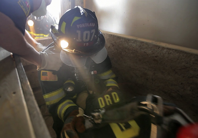 Portland firefighter Roger Robinson tries to lift a downed firefighter up from a confined space during firefighter training at the International Marine Terminal in Portland on Wednesday. Sessions include a number of simulated life-threatening situations.