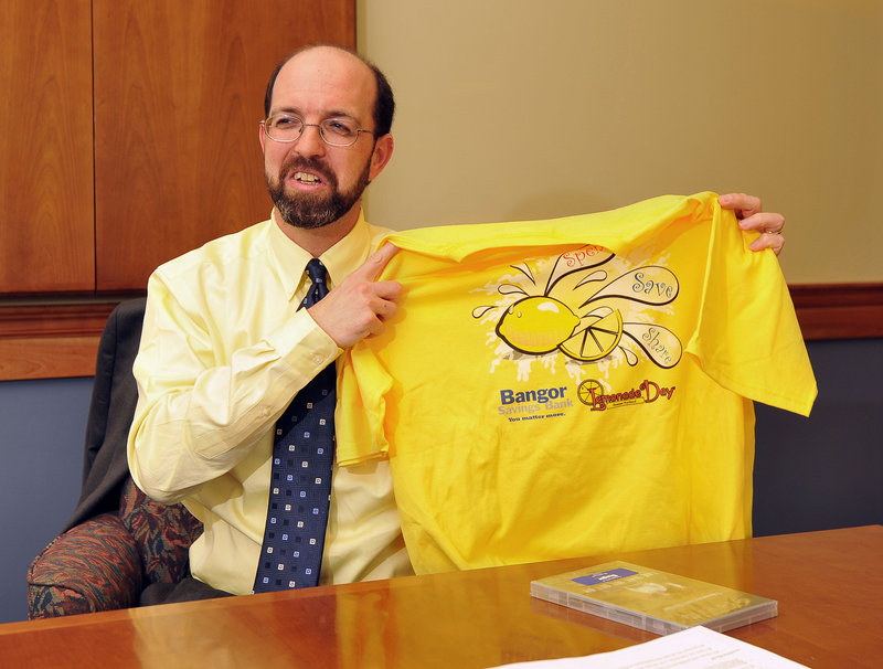 Yellow Light Breen, executive vice president of Bangor Savings Bank, holds up a T-shirt from one of the bank’s community projects.