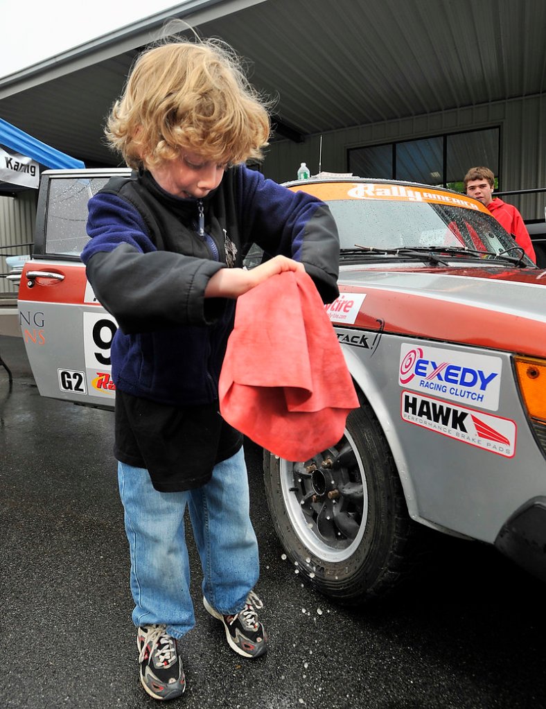 Rhys White, 8, left, wrings out a towel after wiping his father’s Saab 900 at the “Calling All Cars” show Saturday at the Portland Motor Club.
