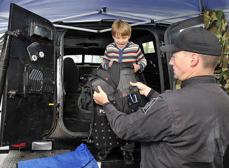 Adrian Boothby, 6, of Portland checks out a bullet-proof vest held by Portland police Sgt. Chuck Libby. Adrian is standing in the armored “Peacekeeper,” which holds 12-14 officers and is built on a Ford F350 truck chassis.
