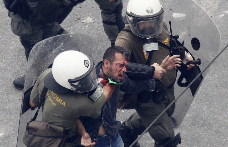 Police arrest a protester Wednesday in Athens. Violence marred the rally when self-styled anarchists overturned umbrellas and chairs from sidewalk cafes to form barricades and hurled rocks at riot police, who used stun grenades and tear gas to disperse the crowds.