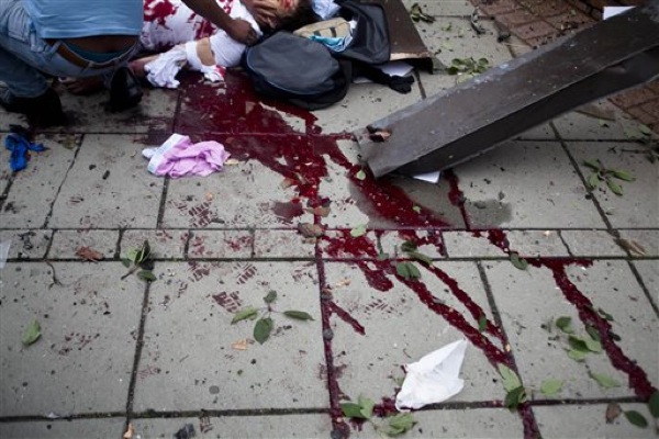 Blood smears the pavement, as a victim is treated outside government buildings in the centre of Oslo, Friday July 22, 2011, following an explosion that tore open several buildings including the prime minister's office, shattering windows and covering the street with documents.(AP Photo/Fartein Rudjord)