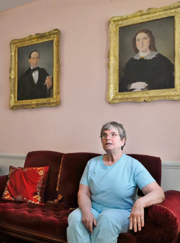 Merry Chapin sits beneath paintings of her great-grandparents, Capt. Reuben and Hannah Blanchard Merrill, at her historic house in Yarmouth, now headquarters for Maine Preservation.
