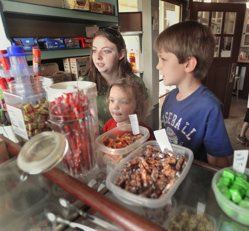 Breonna Hatch helps Saco children Hannah Clarke, 3, and Isaiah Clarke, 7, choose from the candy on display at the Way Way Store.
