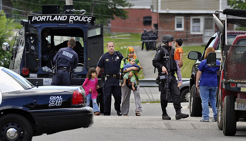 Nicholas Goodman, right, a member of the Special Reaction Team, carries a child after a standoff at the Riverton Apartments complex in Portland in 2011.