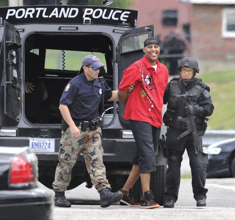 Portland police escort one of six people taken into custody after a standoff at 2 Pinewood Road at the Riverton Apartments.