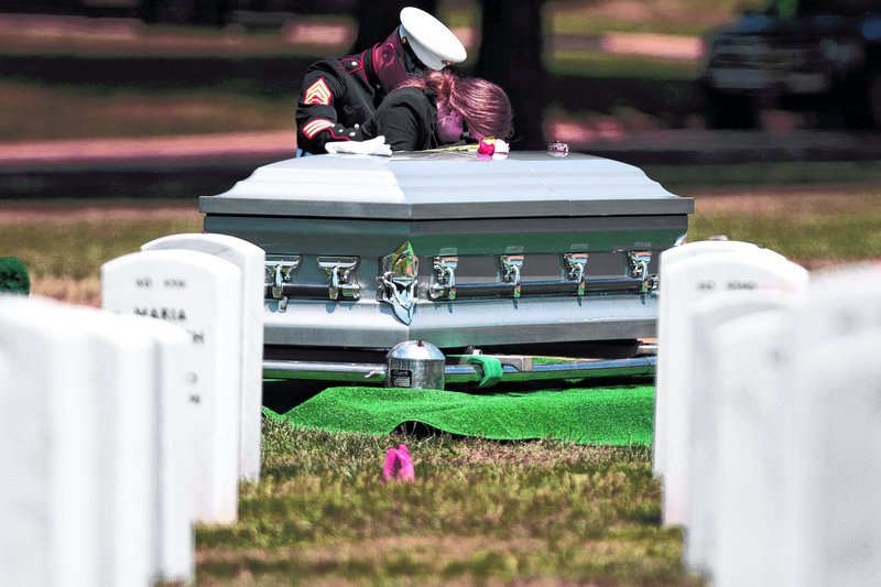 A Marine comforts Amy Balduf of Richmond, Tenn., at Arlington National Cemetery on June 15. Her husband, Marine Sgt. Kevin Balduf, was killed in Afghanistan. The number of U.S. troops killed there so far this year is on pace with 2010.