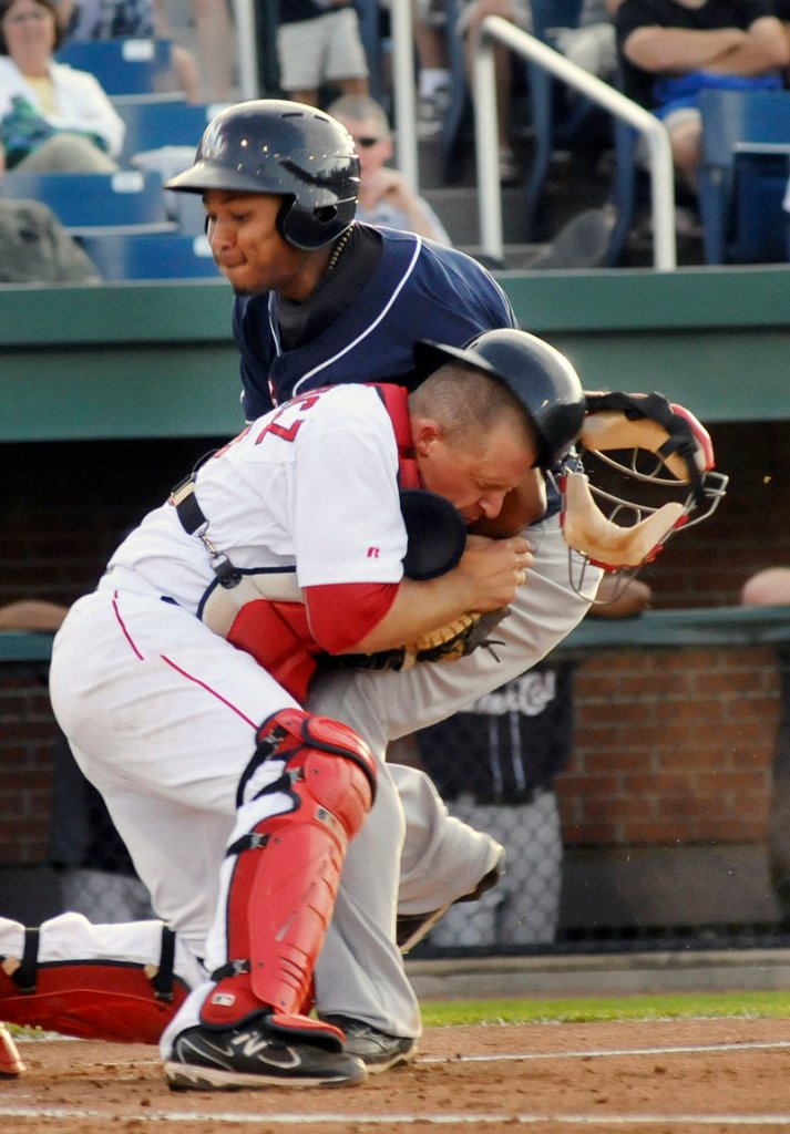 Tim Federowicz, the catcher for the Portland Sea Dogs, takes a hit but holds on to the ball Saturday night to catch Moises Sierra of the New Hampshire Fisher Cats trying to score during the Sea Dogs 8-4 victory at Hadlock Field.