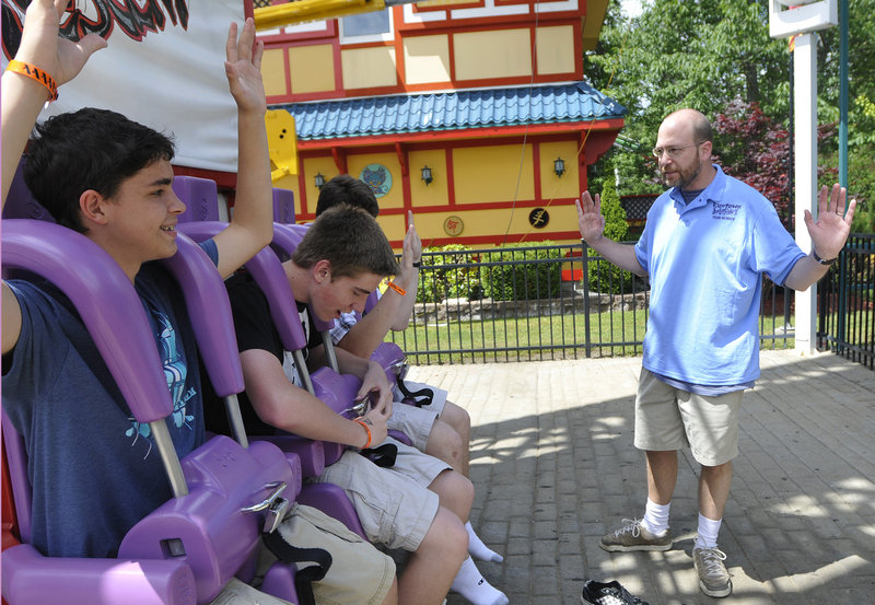 Reporter Ray Routhier asks riders to lift their arms so he can see that they are securely strapped into the Dragon's Descent ride at Funtown Splashtown USA.