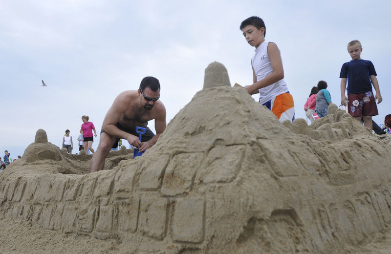 Kosta Kouloufakos of Ottawa, Canada, and his son Nikolas, 12, work on their team's sculpture of a Danish castle during the competition in Ocean Park on Sunday.