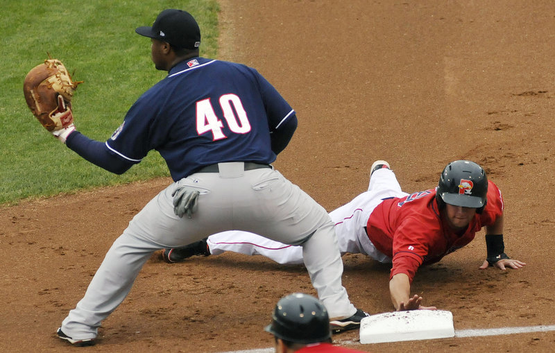Alex Hassan of the Portland Sea Dogs dives back to first base Sunday night as Mike McDade of the New Hampshire Fisher Cats takes a pickoff throw during the Sea Dogs 5-2 victory at a sold-out Hadlock Field.