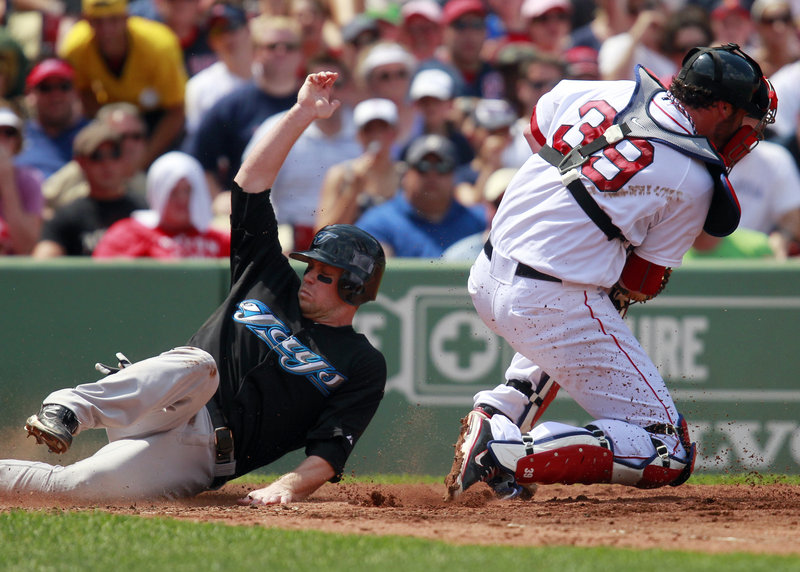 Toronto’s Aaron Hill is safe at home as Boston catcher Jarrod Saltalamacchia takes a late throw in the third inning Monday afternoon at Fenway Park in Boston. Toronto won 9-7, snapping Boston’s win streak at four games.