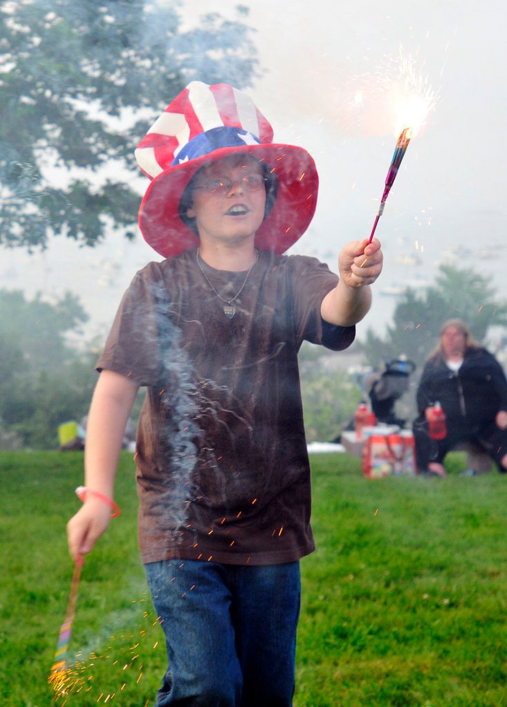 Harrison Nelson, 11, of Saco, celebrates with sparklers before the start of the Fourth of July festivities Monday night.