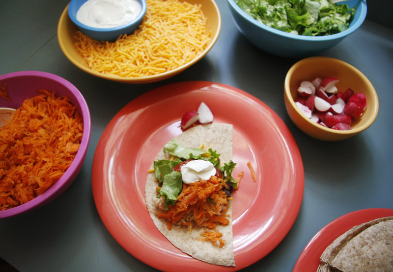 Fresh and local fixings, including grated carrots and shredded greens, are assembled for a rice and bean burrito lunch to be served to the children at the Youth & Family Outreach daycare center in Portland.