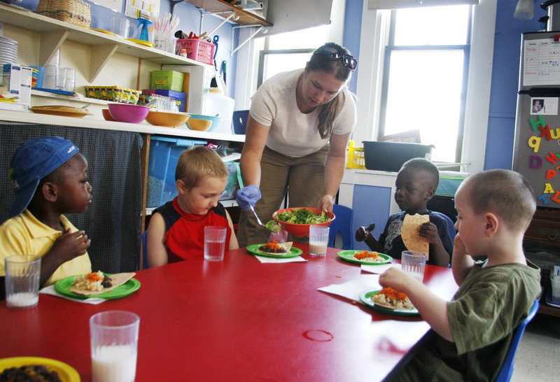 Kayla Landry, a teacher at the Youth & Family Outreach daycare center in Portland, serves lunch to her young charges.