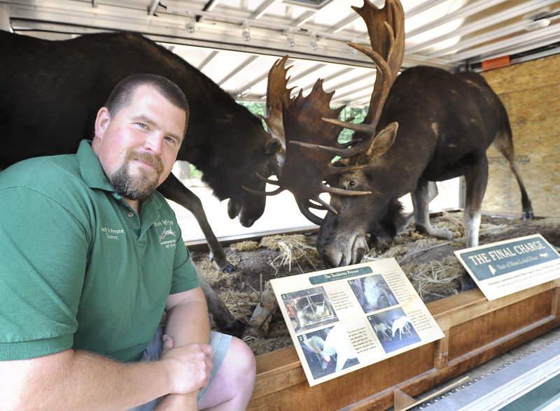 Dufresne sits beside "The Final Charge," on display at the Maine Wildlife Park in Gray.