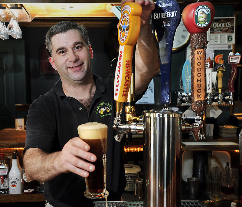 Owner Mike Smith serves a Newcastle Brown Ale, one of many microbrew drafts offered at Maxwell’s Pub & Grill in Ogunquit.