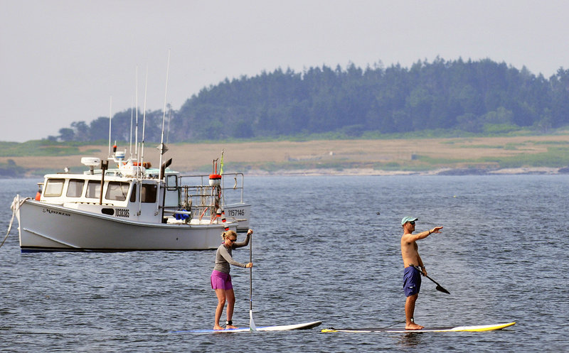 Rafael Adams guides Tonya DiMillo around Kettle Cove during a paddle board lesson last week.