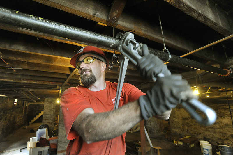 Brian Smith, an employee with Sprinkler Systems Inc. in Lewiston, installs a sprinkler system in the basement of a building being renovated on York Street in Portland.