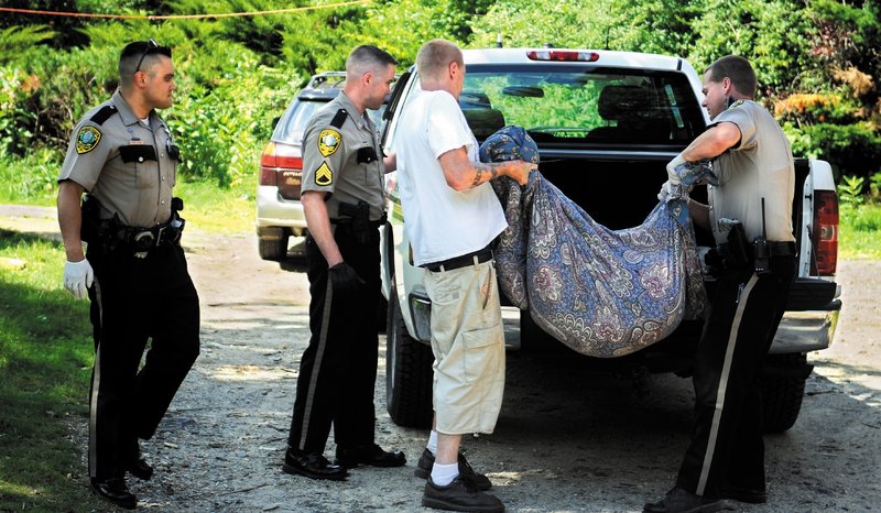 Kennebec County Sheriff’s Sgt. Chris Cowan watches Wednesday as Deputy Joshua Hardy and Jeremiah Bailie load the remains of Bailie’s pit bull Excalibur into a vehicle after a 12-year-old shot the dog during attacks at the Bailie home in Manchester. Bailie, 30, said he had trained his son to shoot the dog if it ever attacked someone. “I didn’t want it to end up being something like this,” he said.