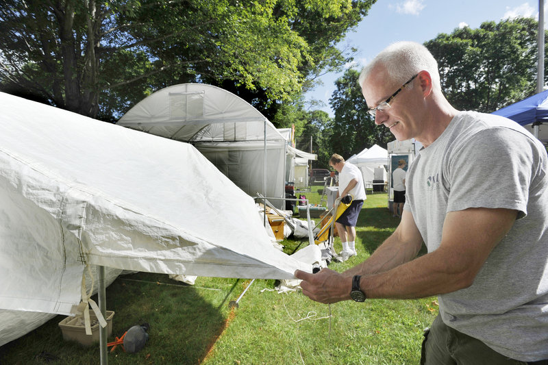 Freeport native Brice Booker, now of Boston, erects a tent Thursday in the crafts area in anticipation of the 46th annual Yarmouth Clam Festival, which begins today. Booker makes and sells fused glass items.John Ewing/Staff Photographer