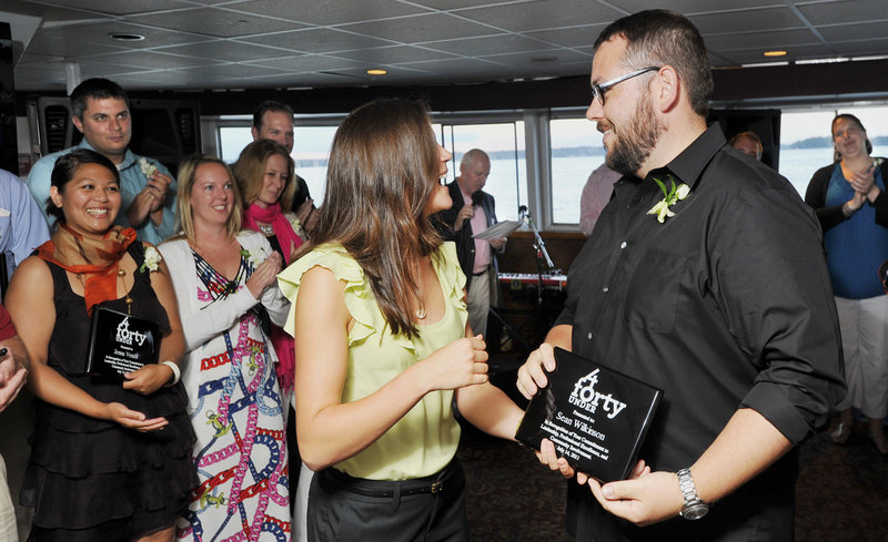 Sean Wilkinson, one of the Forty Under 40 winners, receives his award from Sarah Madeira, administrative assistant to the executive editor of The Portland Press Herald, as other recipients applaud during Thursday night’s tour aboard the Bay Mist cruise ship.