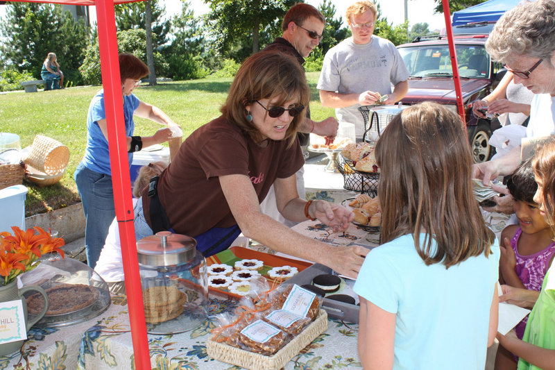 Paula Costin of Sugar Hill Baking serves customers at the opening of the South Portland Farmers Market last Thursday.