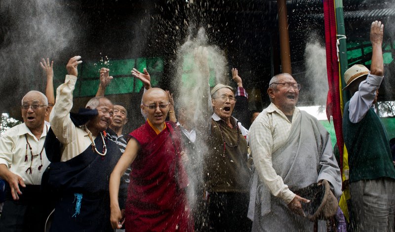 Tibetan exiles throw barley flour in the air Wednesday at the Tsuglakhang temple in Dharmsala, India, as part of celebrations to mark the 76th birthday of the Dalai Lama.