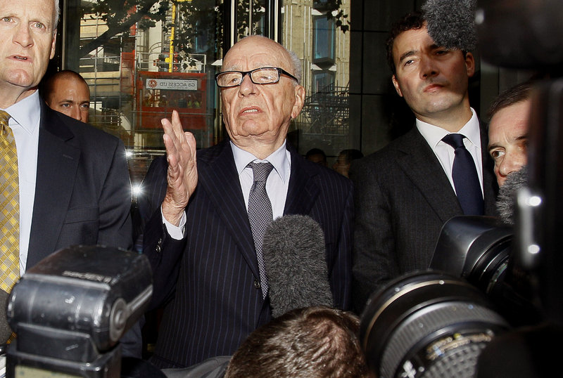 Rupert Murdoch, center, attempts to speak to the media in London on Friday after meeting with the family of murdered schoolgirl Milly Dowler, whose phone was hacked in 2002 by News of the World reporters who were in search of scoops.