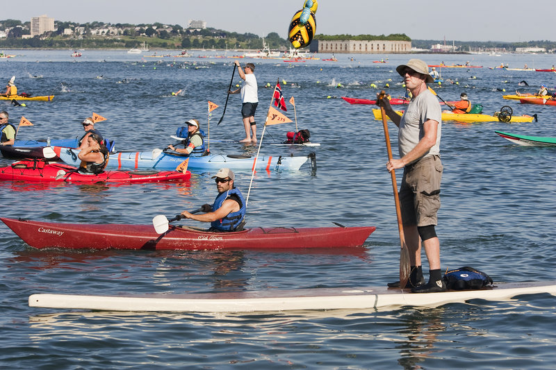 The kayakers and paddleboard escorts, including a Peaks Island summer resident, Steve B. King, standing in foreground, wait to accompany the swimmers Saturday as the race to Portland is about to begin.